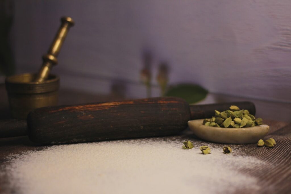 A close-up shot of fresh green okra pods and dried whole cloves arranged aesthetically on a rustic wooden surface with a