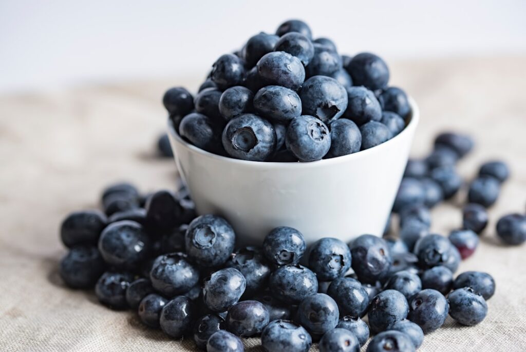 A vibrant close-up shot of fresh ginger root and ripe blueberries on a rustic wooden surface with soft natural lighting