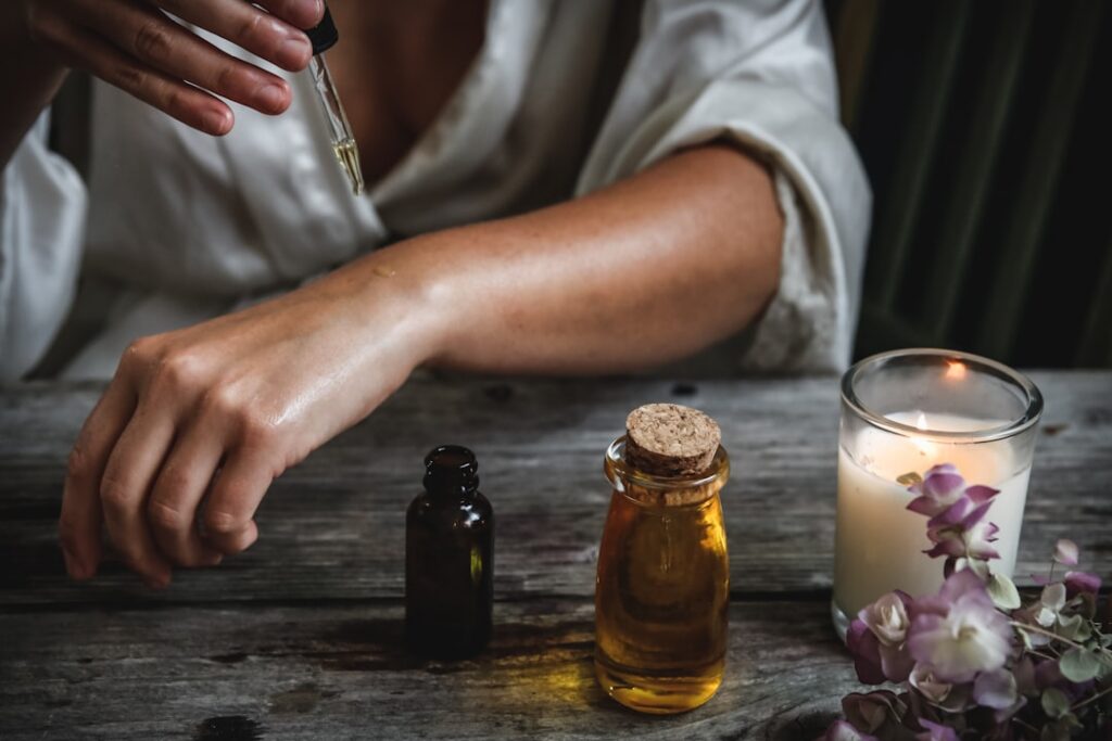 A close-up of a person s hands gently mixing a small amount of Vaseline with a few drops of a golden oil in a clear smal