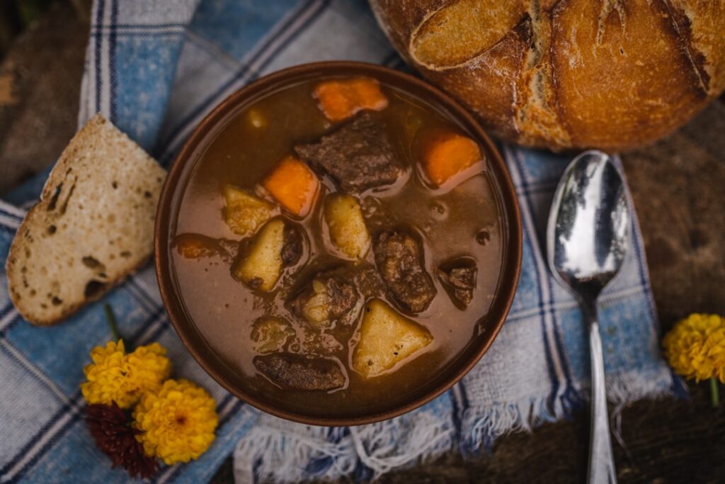 A close-up shot of a richly colored perfectly cooked plant-based stew with visible tender vegetables and legumes garnish