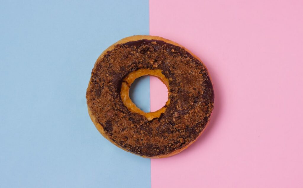 A freshly made cinnamon sugar donut coated generously with a mix of cinnamon and granulated sugar on a simple white plat