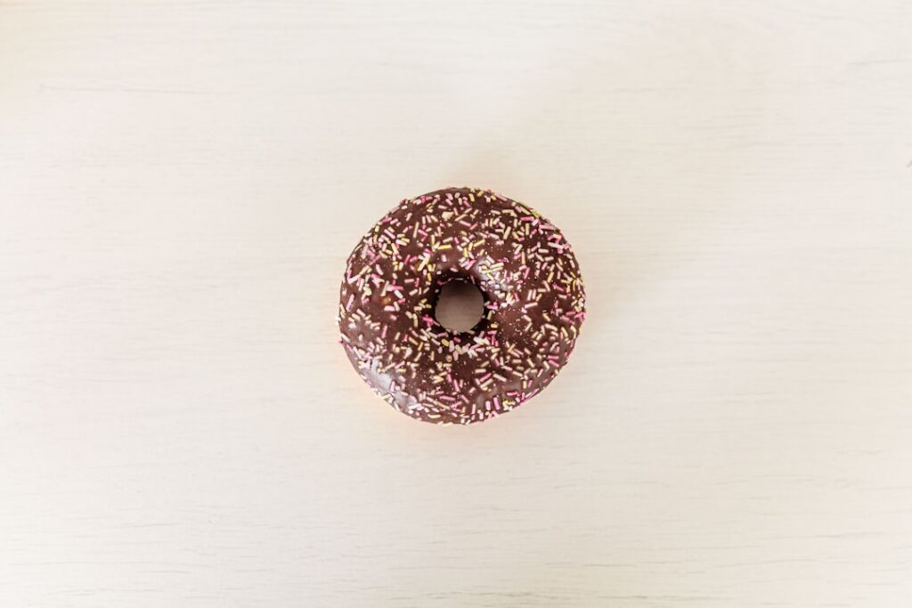 A homemade donut with a thick glossy chocolate frosting on top on a white plate