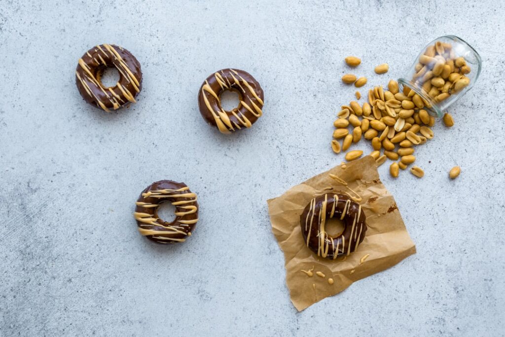 A homemade donut with a smooth caramel glaze and toasted almond slices sprinkled on top on a white plate
