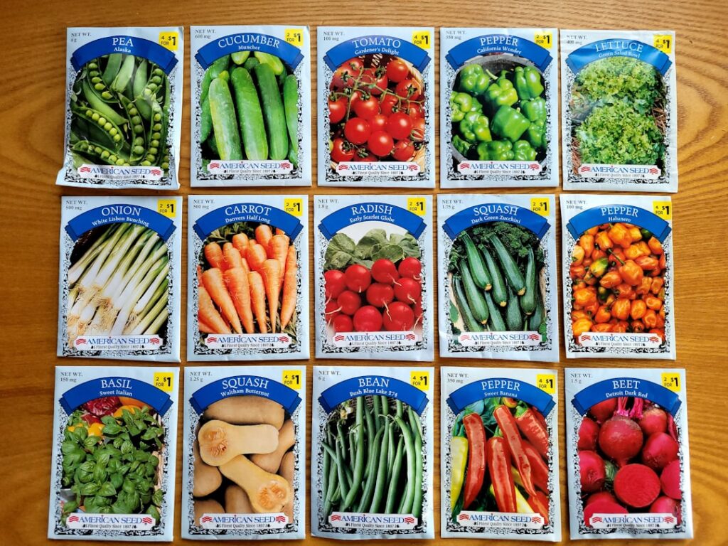 An assortment of various seeds in small packets and a gardening hand placing seeds into a small container with potting m