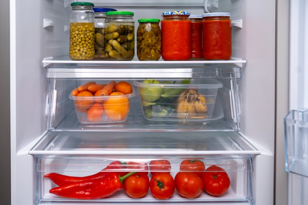 Several small labeled plastic bags or containers with moist seeds inside neatly arranged on a refrigerator shelf