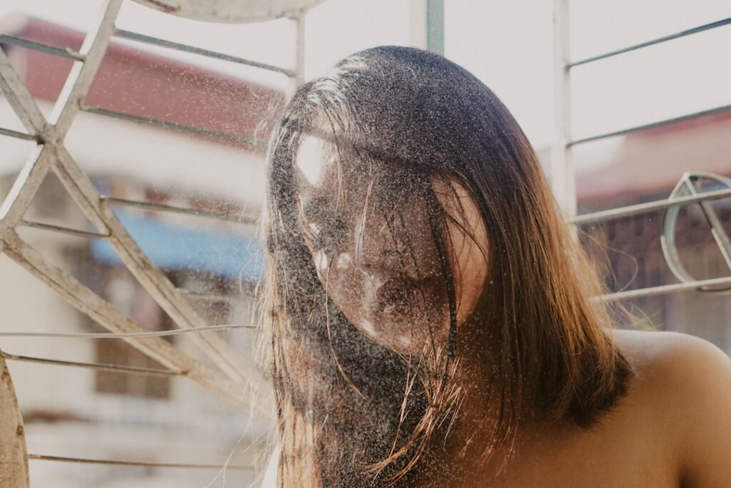 A woman rinsing her hair under a shower with water flowing and her hair looking clean and shiny