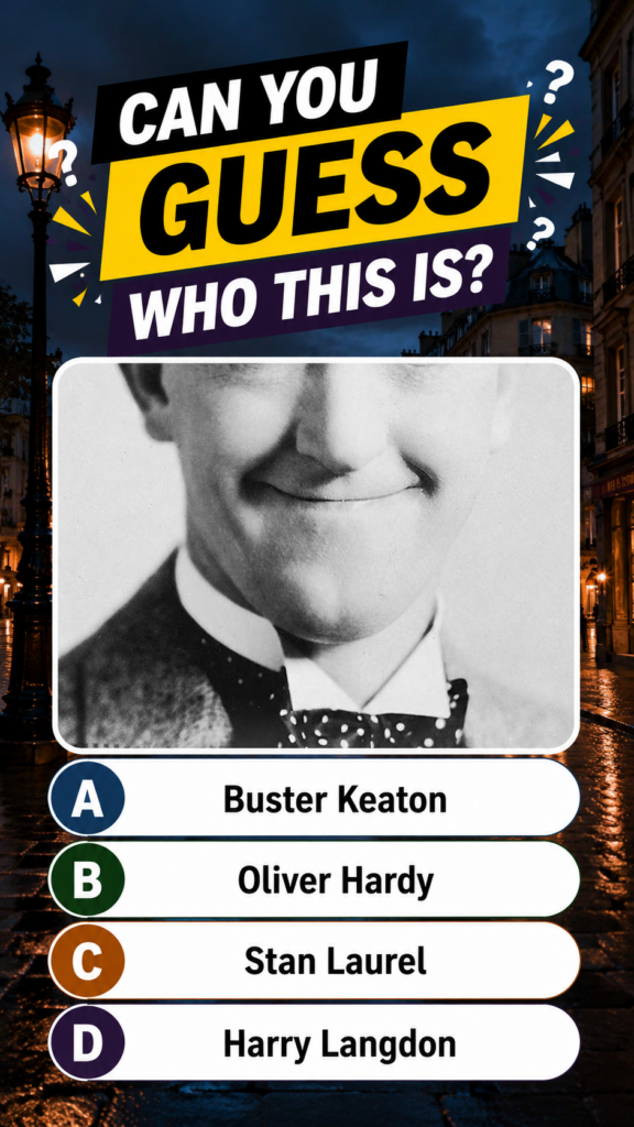 A black-and-white cropped portrait of Stan Laurel with a timid smirk and polka-dot bowtie set against a dark rainy Europ