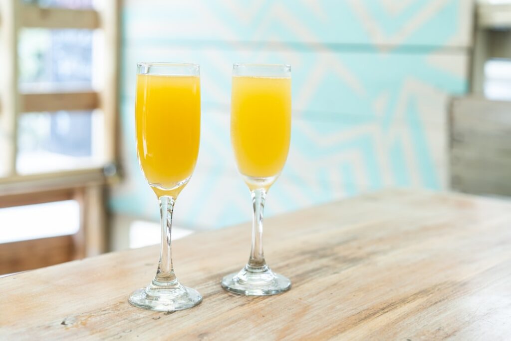 A beautiful cranberry orange mimosa in a champagne flute garnished with an orange slice and fresh cranberries