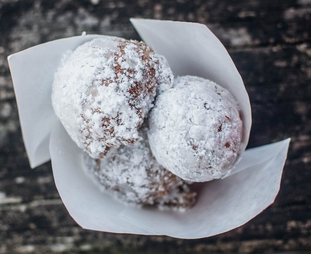 Golden brown twisted donuts dusted with powdered sugar on a cooling rack