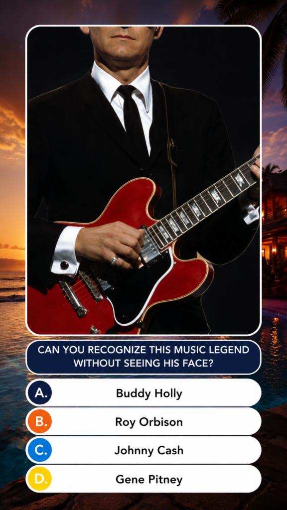 A male musician shown from the nose down dressed in a classic black suit white shirt and black tie wearing a silver ring