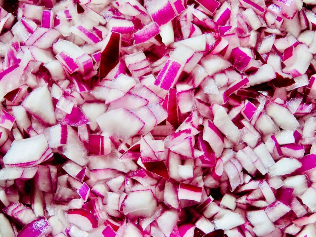 Close-up of chopped red onions simmering in a pot of water on a stovetop