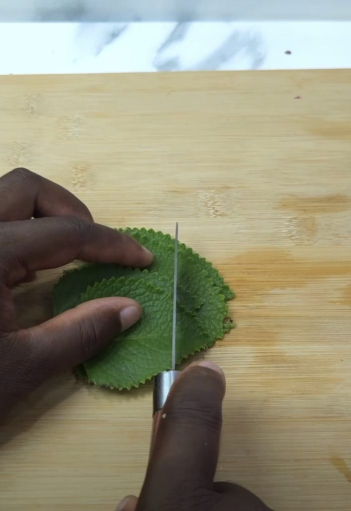 Hands slicing fresh green leaves on a cutting board an overhead shot showing the process of preparing ingredients for he