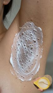 A woman applying a natural paste to her underarm area which appears smooth and free of bumps The setting is a clean brig