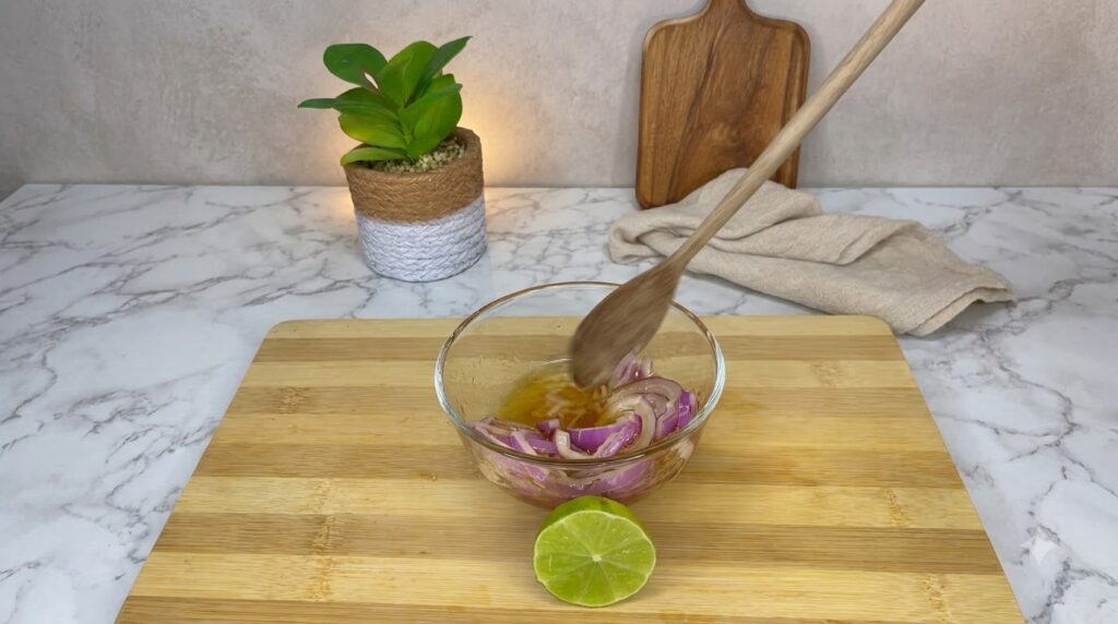A refreshing glass of lemon ginger detox drink with fresh lemon slices and ginger root set on a bright kitchen counter