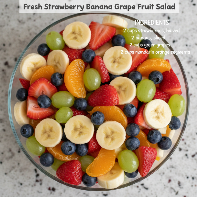 A vibrant overhead shot of a fresh strawberry banana grape blueberry and mandarin orange fruit salad in a clear glass bo