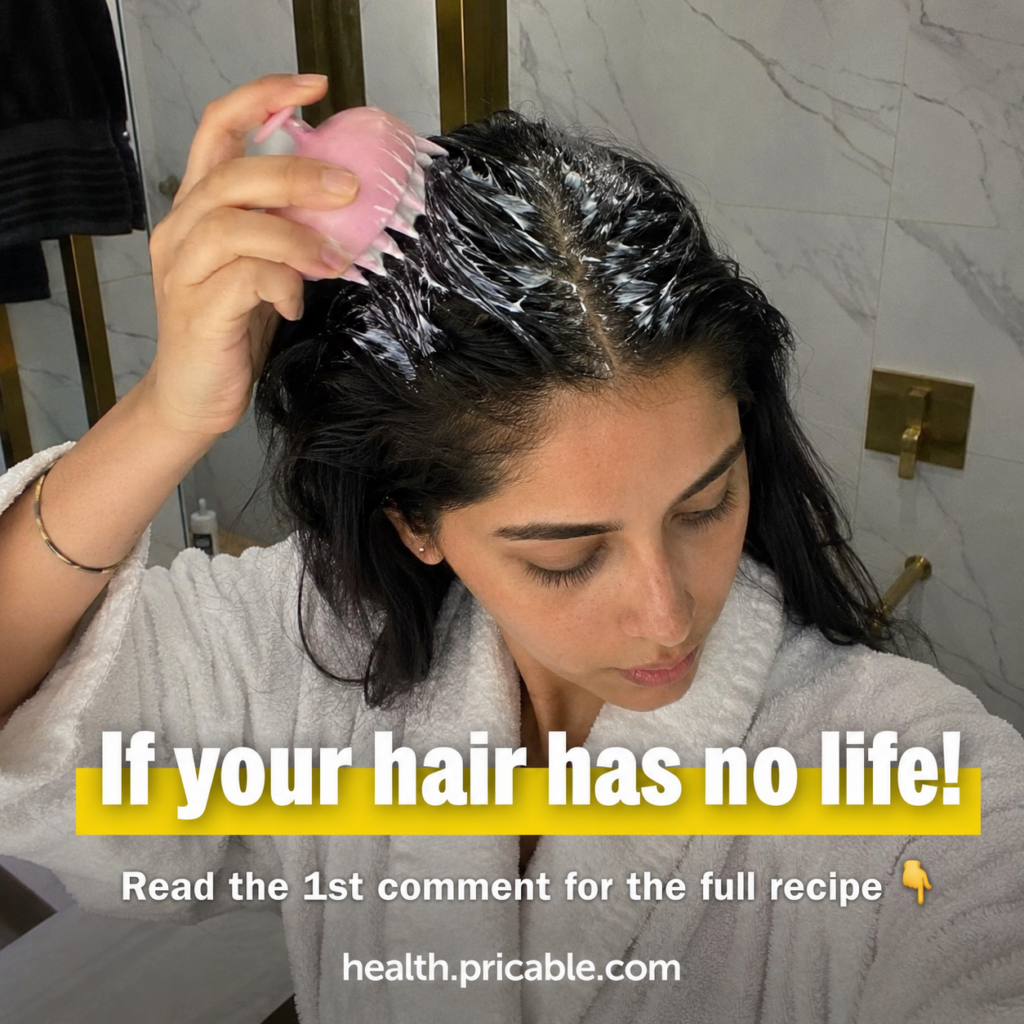A woman in a white bathrobe is applying a creamy white product to her scalp with a pink claw-like scalp massager Her dar