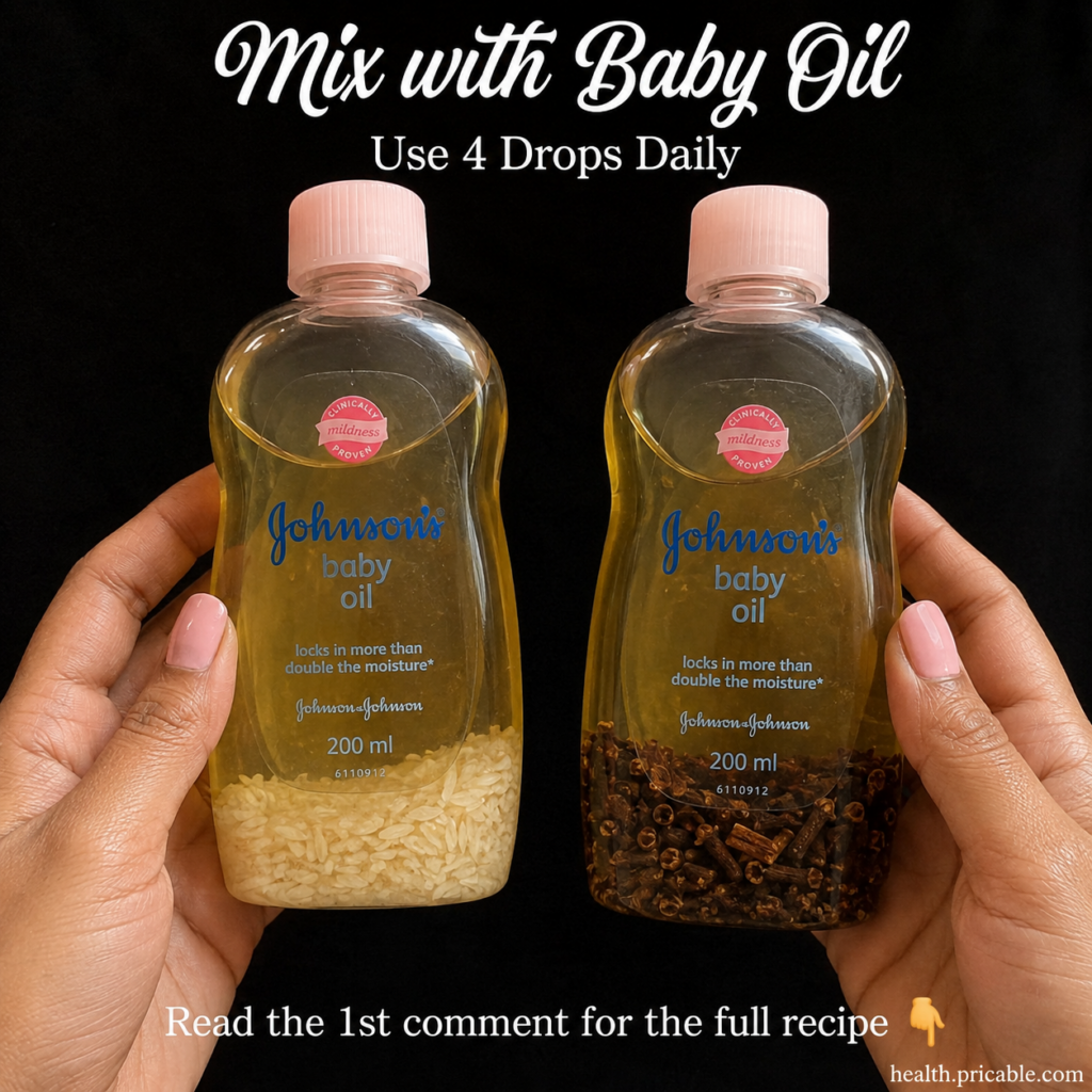 Two hands holding two bottles of Johnson s baby oil one infused with rice and one with cloves against a black background