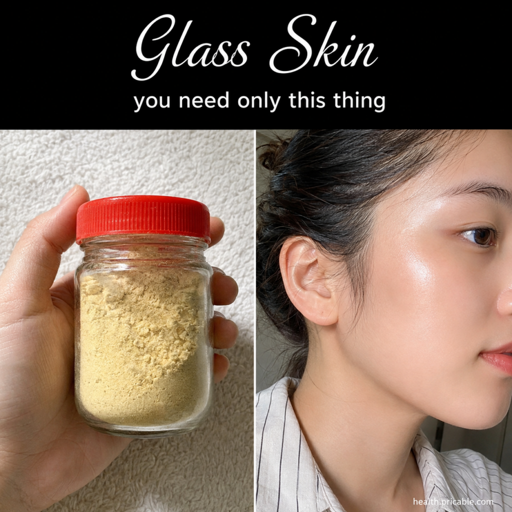 A hand holding a small clear glass jar with a vibrant red lid filled with light yellow finely ground powder against a so