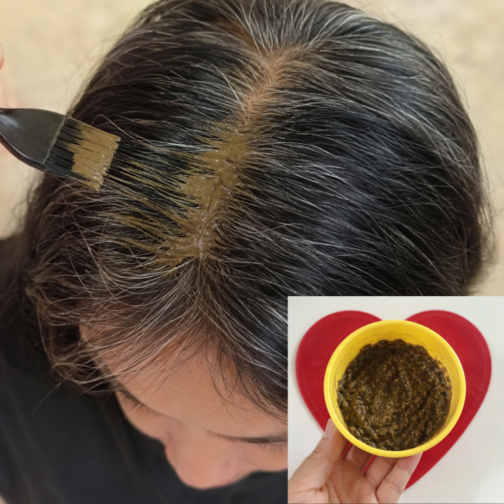 Close-up overhead view of a person s scalp and dark hair with visible gray roots while a brush applies a thick brownish-