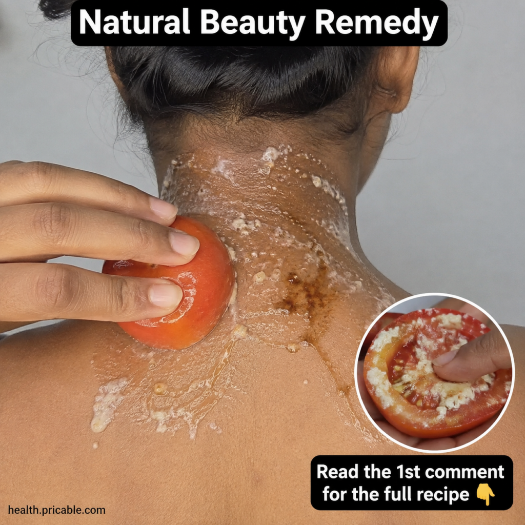 A hand gently rubbing a halved red tomato with a white granular paste onto the back of a person s neck which has darker 