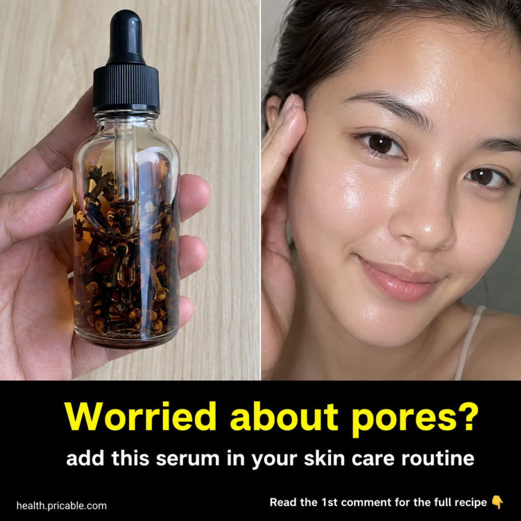 A clear glass dropper bottle filled with a golden-amber liquid and whole dried cloves held by a hand against a light nat