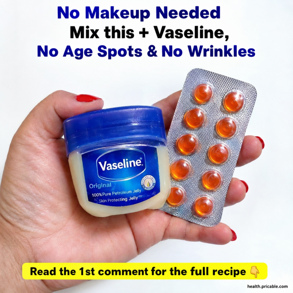 A hand holding a tub of Vaseline petroleum jelly and a blister pack of orange Vitamin E capsules against a clean white b