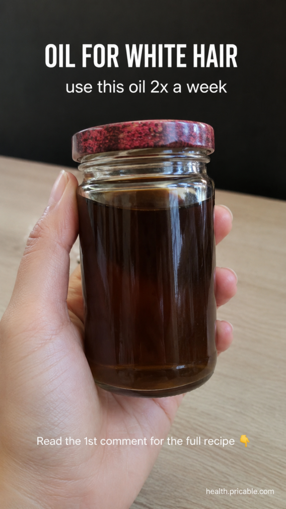 A hand holding a clear glass jar filled with dark hair oil with text overlays OIL FOR WHITE HAIR and use this oil 2x a w