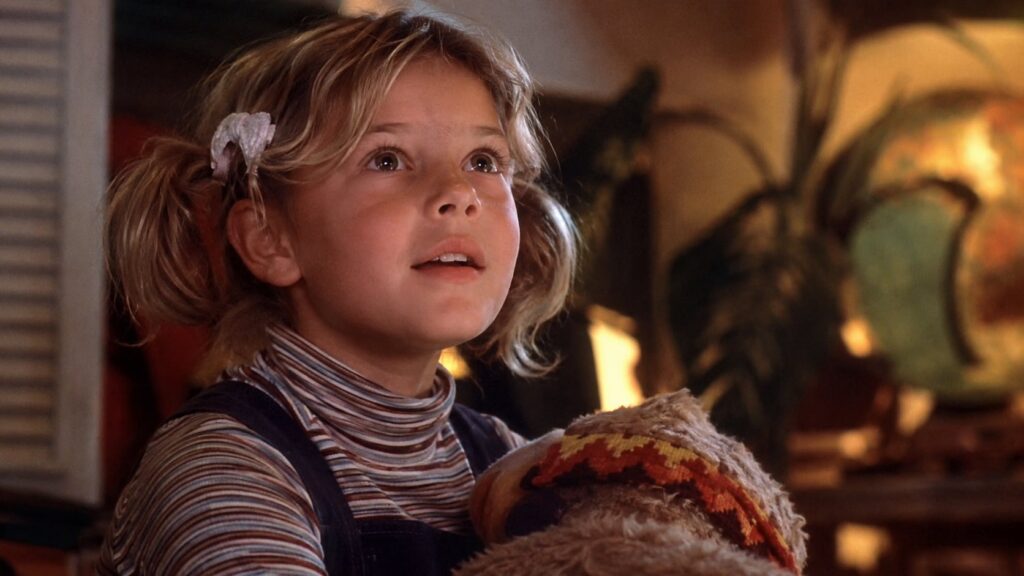 A film still of Drew Barrymore in her iconic role as Gertie from E T the Extra-Terrestrial looking up with wide curious