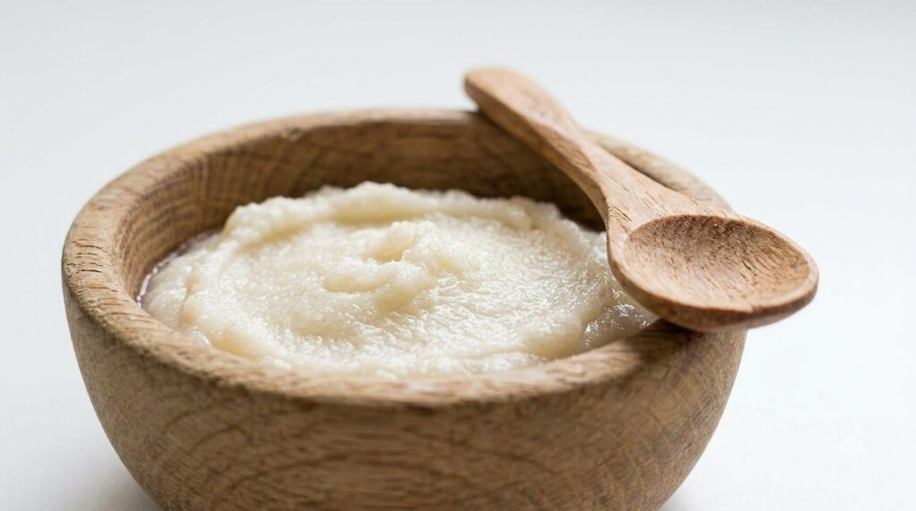 A close-up of a bowl containing the homemade scrub paste with a small spoon ready for application against a bright clean