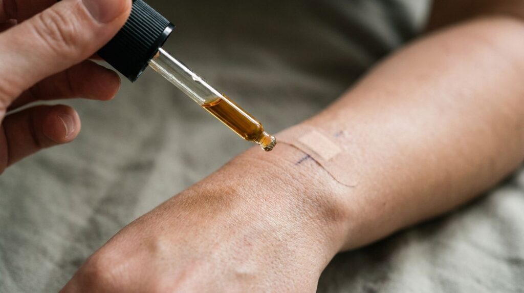 A close-up of a hand gently applying a dropper of oil to the back of another hand for a patch test