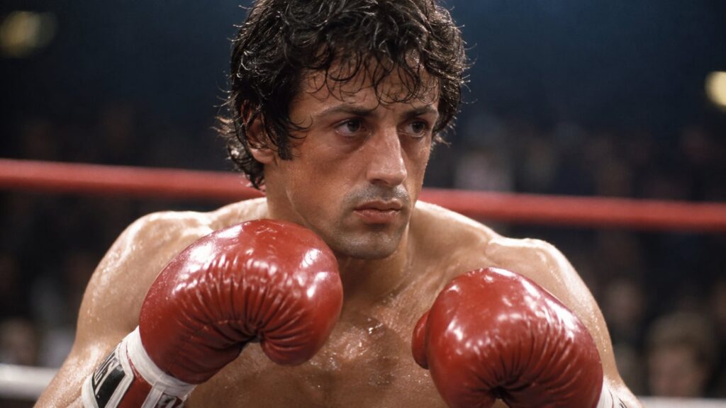 A still image from the movie Rocky showing Sylvester Stallone as Rocky Balboa with his boxing gloves looking determined 