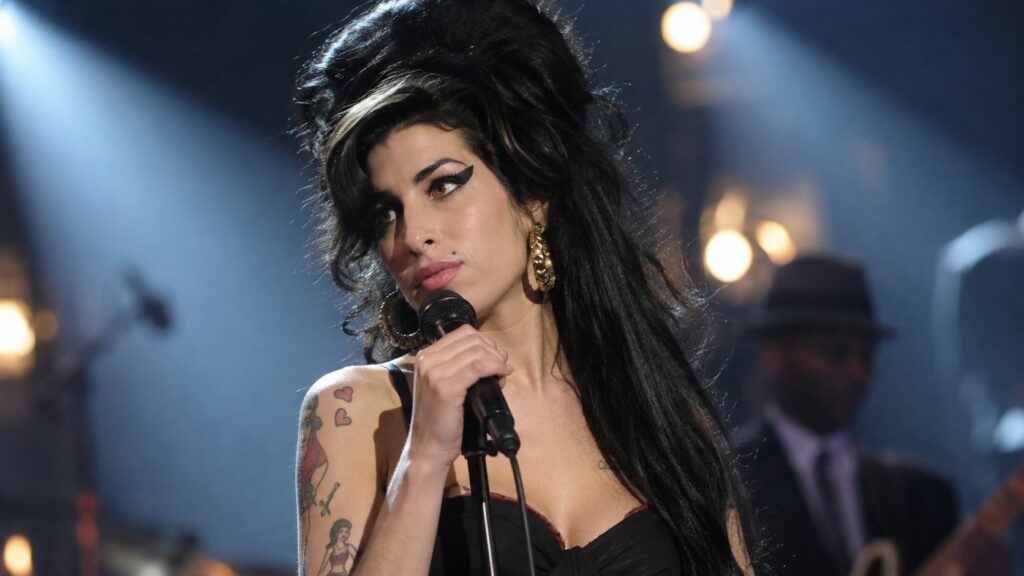 Amy Winehouse with her iconic beehive hairstyle and winged eyeliner singing passionately on stage