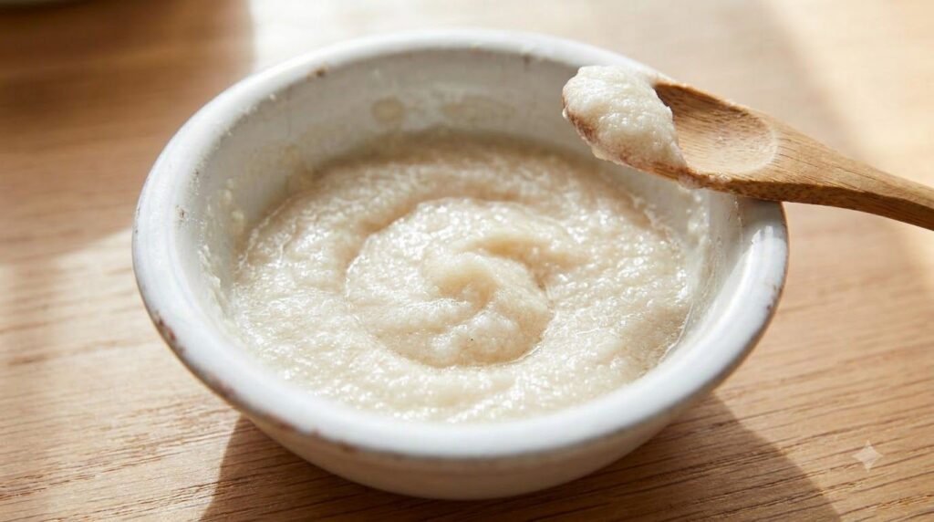 A close-up shot of a small white ceramic bowl containing the freshly mixed paste made from baking soda honey and water w