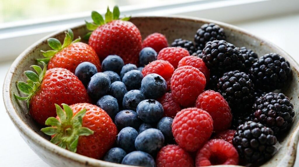 A close-up of various fresh ripe berries like strawberries blueberries raspberries and blackberries glistening with a sl