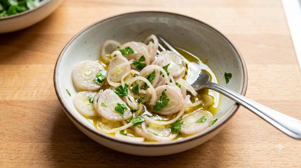 A close-up of thinly sliced shallots mixed with fresh parsley and olive oil ready to be used as a topping or an ingredie