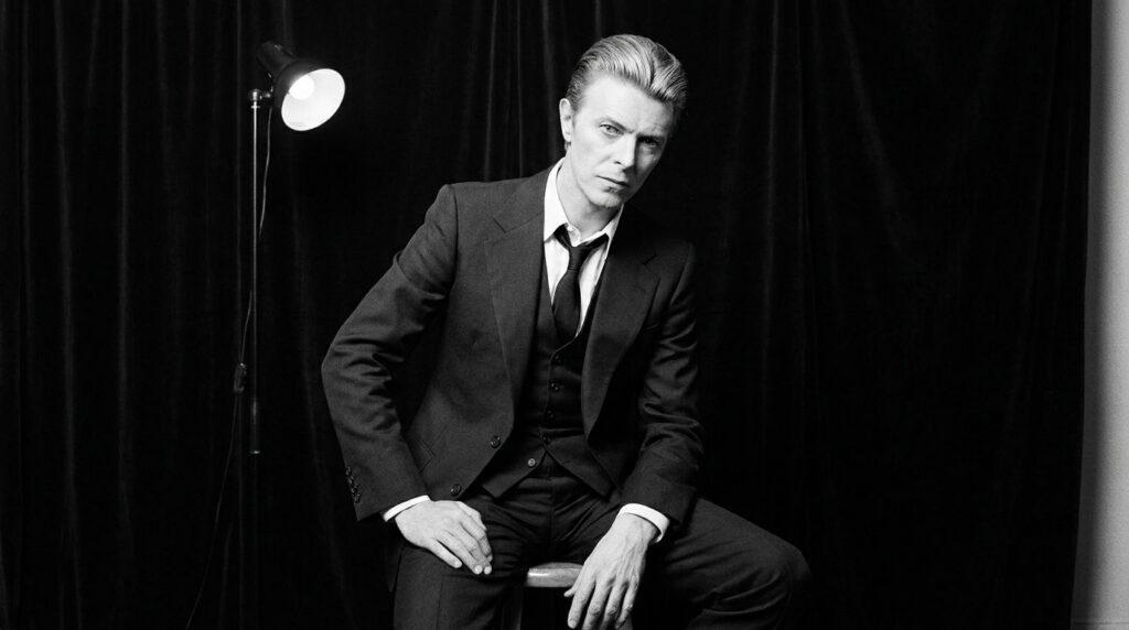 David Bowie as the Thin White Duke elegantly dressed in a sharp suit with slicked-back hair looking sophisticated and in