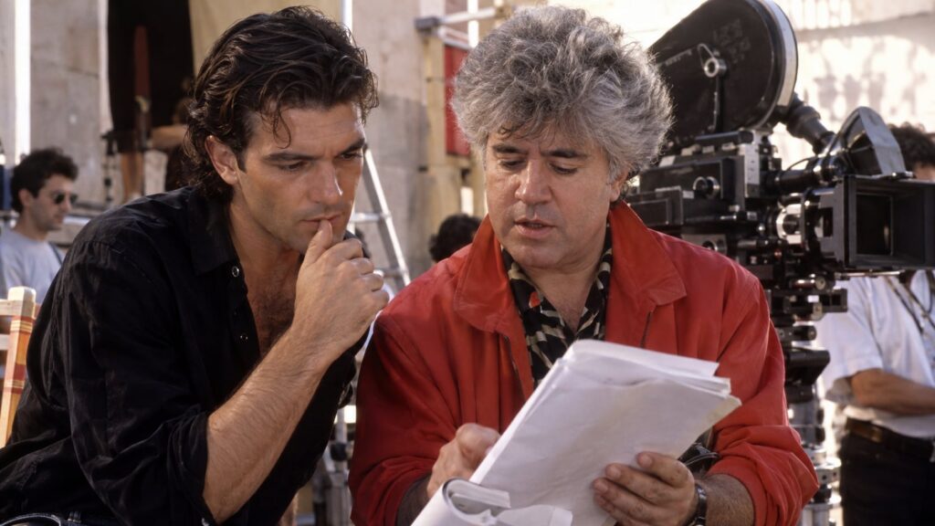 A vintage photo of Antonio Banderas and Pedro Almodóvar on a film set in the 1980s perhaps discussing a scene reflecting