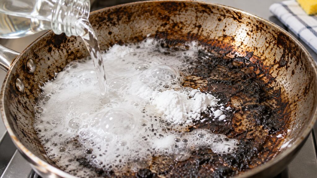 Baking soda and white vinegar fizzing in a burnt pan illustrating the cleaning reaction