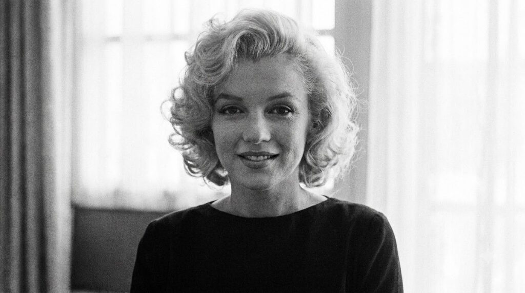 A classic black and white portrait of Marilyn Monroe smiling