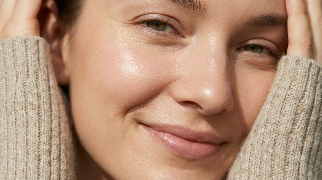 Close-up of a woman s face with visibly smooth hydrated and glowing skin showing a glass skin effect Her complexion is e