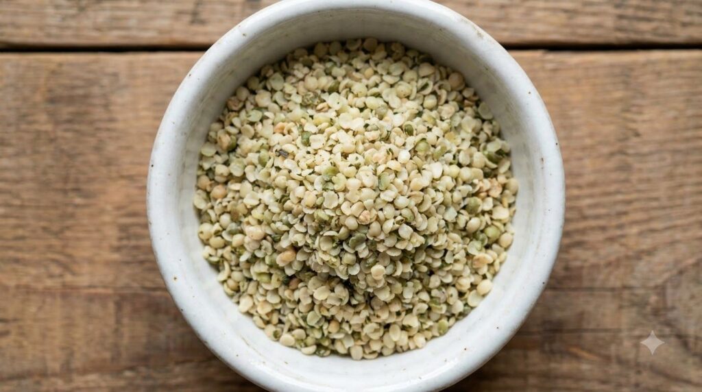 A close-up of a bowl of hulled hemp seeds showing their small light green and tan appearance