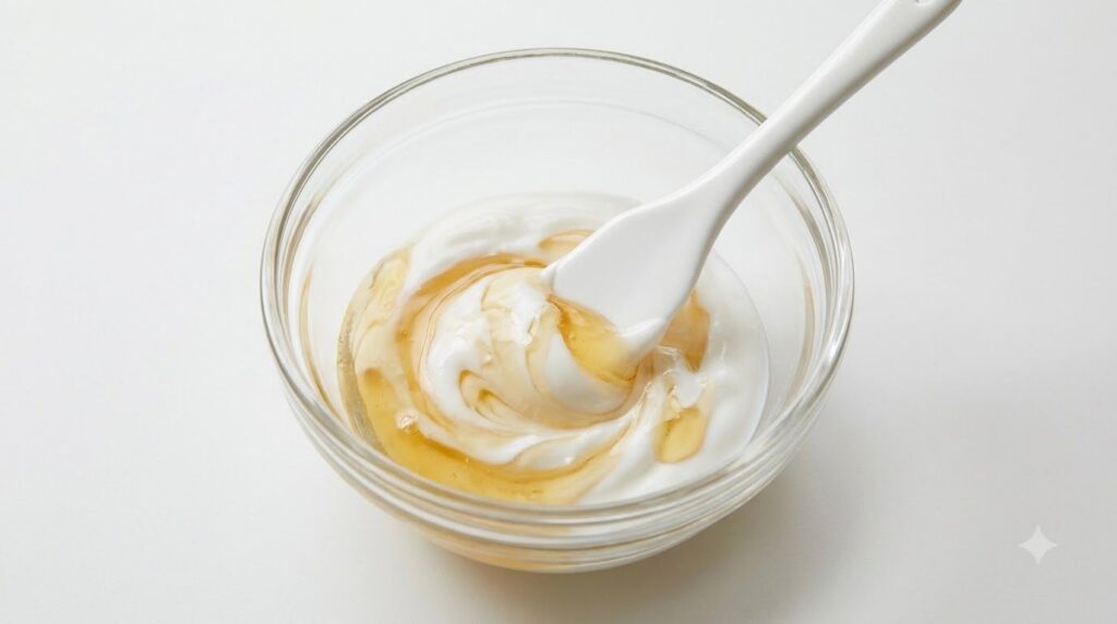 Close-up of a small bowl with Pond s cream and honey being mixed with a spatula
