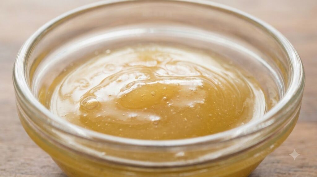 A close-up of a small glass bowl with the smooth mixed Vaseline and honey blend ready for application
