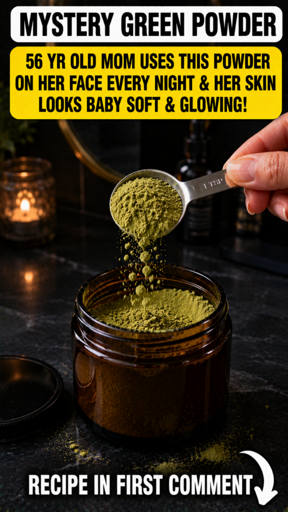 A hand pouring vibrant green moringa powder from a measuring spoon into an amber glass jar with a flickering candle in t