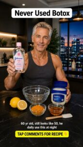 A smiling man in a modern kitchen holding Vaseline and Johnson s Baby Oil with lemons turmeric and honey on the counter 