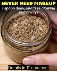 A close-up of a glass jar filled with a beige-pink collagen powder blend with a small wooden spoon resting in it The bac