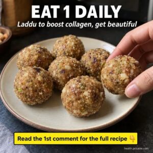 A beautiful close-up of a perfectly round golden-brown Laddu garnished with chopped nuts sitting on a traditional Indian