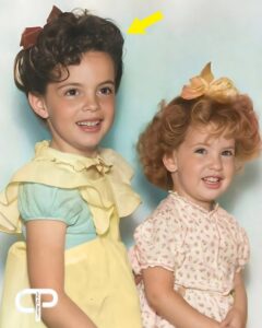 A black and white photo of a young Linda Gray as a child with an arrow pointing to her standing next to a younger girl i