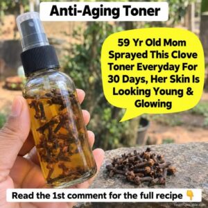 A close-up shot of whole cloves in a small bowl next to a clear glass bottle of homemade clove toner with a few cloves i