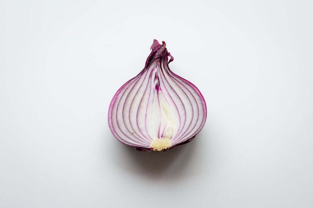 A person s hands are shown squeezing chopped onion through a cheesecloth to extract its juice into a small ceramic bowl 